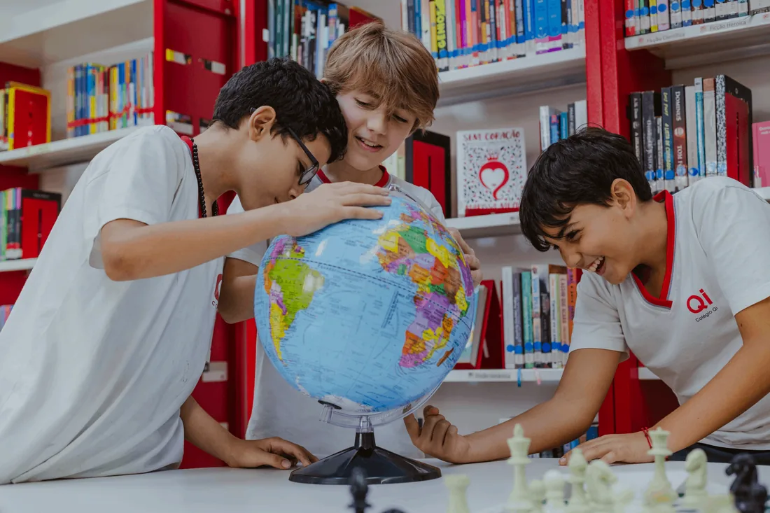 Alunos explorando um globo em atividade escolar